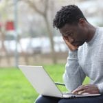man experiencing burnout, head on hand, string at laptop