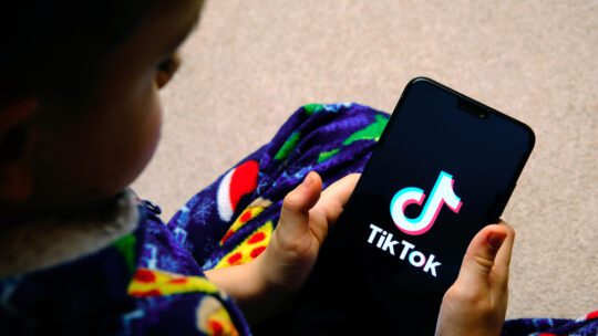 child holding a phone with tiktok app on screen