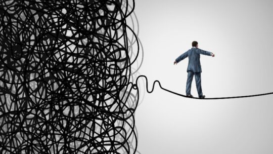 Crisis Management business concept as a tightrope walker walking out of a confused tangled chaos of wires breaking free to a clear path of risk opportunity as a metaphor for managing organizations.