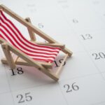 Red beach chair on white blank calendar background copy space. Annual leave travel period for relaxation concept. Period of paid time off (PTO) granted to employees by their employer.