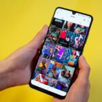 Woman surfing on TikTok showing most popular TikTok videos in a grid on the app on her phone.
