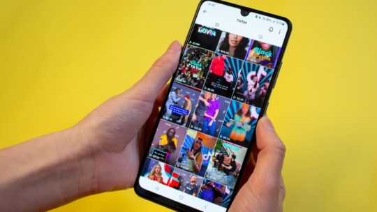 Woman surfing on TikTok showing most popular TikTok videos in a grid on the app on her phone.