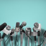 Press conference with standing microphones on an aqua blue background